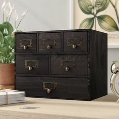 an old black filing cabinet sitting on top of a wooden table next to a clock