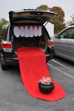 an open car trunk with toothy teeth and a bowl of candy on the floor