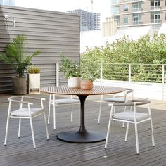 an outdoor table and chairs on a wooden deck with potted plants in the background