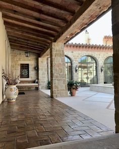 an outdoor patio with potted plants on the side and brick walkway leading up to it