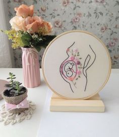 there is a small vase with flowers in it next to a cross - stitch project