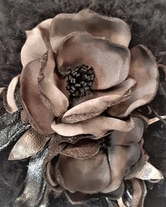 a close up of a flower on a black surface with silver foil and fur around it