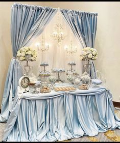 a table covered in blue cloths and white flowers next to a chandelier