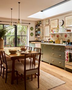 a dining room table and chairs in front of an open window with lots of pictures on the wall