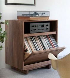 an old record player is sitting on top of a wooden shelf next to a potted plant