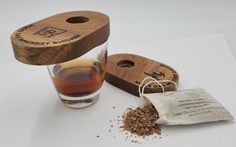 a cup of tea next to a bag of ground spices and a wooden holder for a spice dispenser