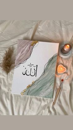 a greeting card with arabic writing on it next to candles and some feathers in the background