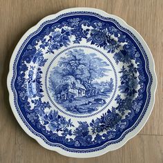 a blue and white plate sitting on top of a wooden table next to a wall