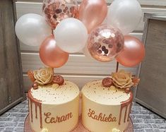 two cakes on a table with balloons and cupcakes