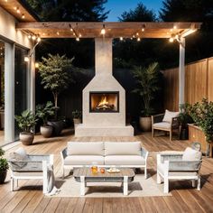 an outdoor living area with white furniture and fire place in the center, surrounded by wooden decking