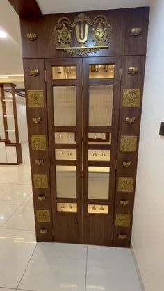 two wooden doors with gold designs on them in a room that has white tile flooring