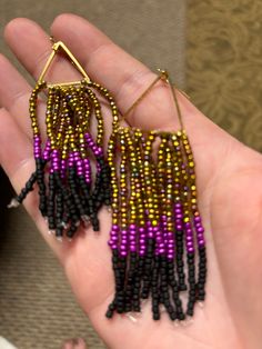 Dangling earring.  Purple, gold, and black beaded.  Hand made. Black Dangle Hoop Earrings For Festivals, Gold Beaded Earrings With Ear Wire For Party, Gift Black Beaded Dangle Jewelry, Dangle Jewelry With Gold Beads For Party, Gift Black Dangle Beads Jewelry, Gold Beaded Drop Earrings For Party, Party Gold Beaded Drop Earrings, Festival Earrings With Gold Beads, Black Bohemian Earrings With Ear Wire