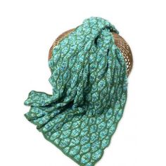 a green and blue scarf sitting on top of a wicker basket