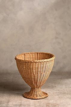 a wicker bowl sitting on top of a white floor next to a gray wall