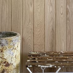 a wooden bench sitting next to a metal trash can on top of a white table