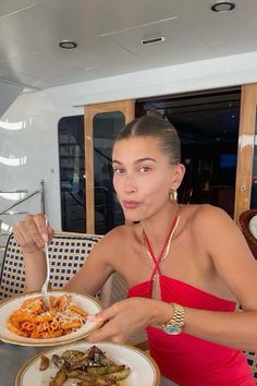 a woman sitting at a table with plates of food in front of her on the boat