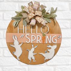 a wooden sign that says hello spring with rabbits and carrots