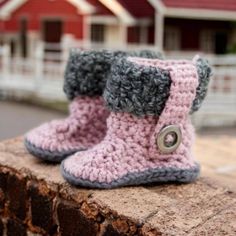 a pair of crocheted boots sitting on top of a brick wall next to a house