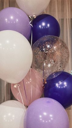 there are many balloons in the air and one is purple, white and silver colors