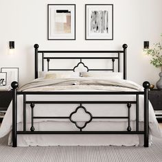 a black metal bed frame in a white bedroom with pictures on the wall above it