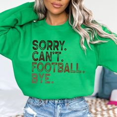 a woman wearing a green sweatshirt that says sorry can't football bye