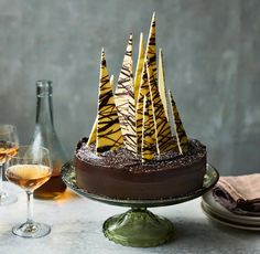 a chocolate cake decorated with zebra print icing and wine glasses on a table next to it