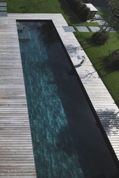 an aerial view of a swimming pool in the middle of a yard with grass and trees