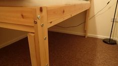 a wooden bed frame sitting on top of a hard wood floor next to a lamp