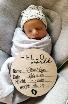 a baby wrapped in a blanket is holding a sign