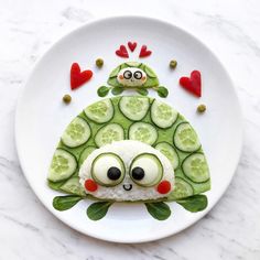 a white plate topped with cucumber slices and an owl made out of cucumbers