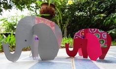 two wooden elephants sitting next to each other on top of a tile floor in front of trees