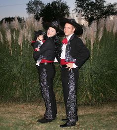 two people dressed in black and red standing next to each other with grass behind them