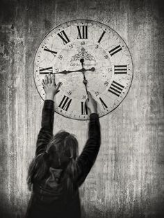 a girl holding up a clock on the wall