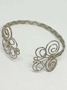 "This is a beautiful handmade piece created by Mimi.  This adjustable bracet is made with 20 gauge stainless steel wire. It was wire weaved with 28 gauge stainless steel into a V pattern. The spirals are shaped like 2 butterflies giving it a beautiful Bohemian style. Measures approximately 2.6\" in diameter. 8\" around Check out the matching adjustable rings." Handmade Adjustable Spiral Cuff Bracelet, Adjustable Metal Spiral Cuff Bracelet, Adjustable Spiral Wire Wrapped Bracelets, Adjustable Spiral Nickel-free Jewelry, Elegant Wire Wrapped Spiral Bracelets, Adjustable Wire Wrapped Cuff Bracelet, Handmade Adjustable Spiral Jewelry, Elegant Spiral Wire Wrapped Bracelets, Elegant Spiral Wire Wrapped Bracelet