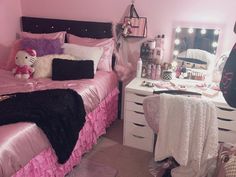 a bedroom with pink and black bedding, white dressers and mirror on the wall