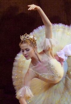 a ballerina is performing on stage with her arms in the air and one arm out