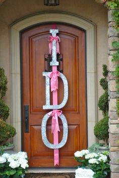 the front door is decorated with pink ribbon and white hydranges, along with two large metal letters that spell out dad