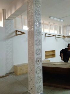 a man sitting on top of a wooden bench in a room with white walls and flooring