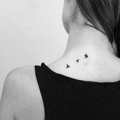 the back of a woman's neck with three birds on it