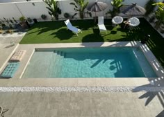 an aerial view of a pool with chairs and umbrellas in the back yard area