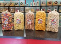 three bags of popcorn sitting on top of a counter next to each other in front of bins