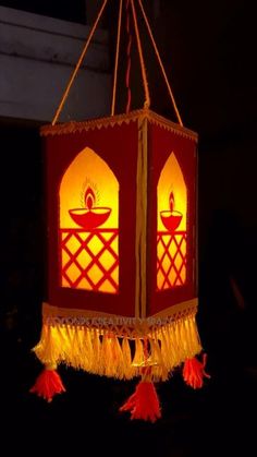 a red and yellow lantern with tassels hanging from it's sides in the dark