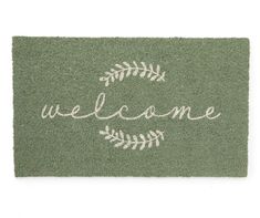 a welcome mat with the word welcome written on it in white lettering and green grass