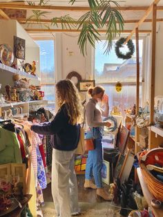 two women standing in a room with lots of items