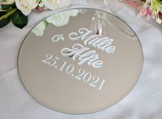 a personalized glass mirror with the names and date on it next to some flowers