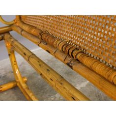 a close up of a wooden bench with wicker back and seat paddings