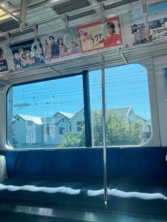 the inside of a train car with posters on the wall and windows in front of it