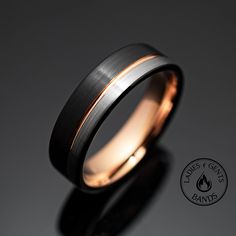 a black and gold wedding ring with a rose in the center on a dark background