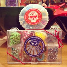 two plastic containers with beads and candy in them sitting on a table next to other items