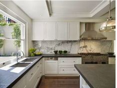 a large kitchen with white cabinets and black counter tops, along with an island in the middle